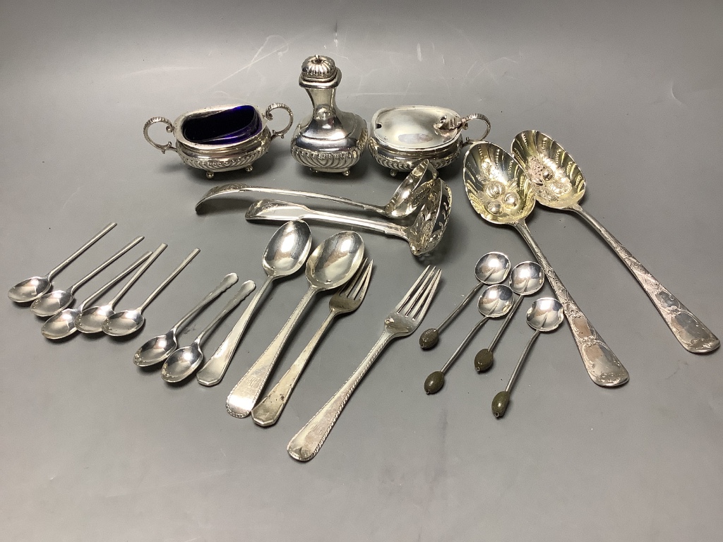 A three-piece silver condiment of oval half-reeded form, two silver sifter spoons, a pair of silver berry spoons and sundry silver flatware, approximately 18oz